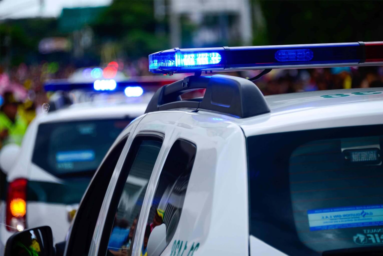 Imagine cu girofarele unei masini de politie in prim plan, o alta masina de politie cu girofarele pornite in fundal